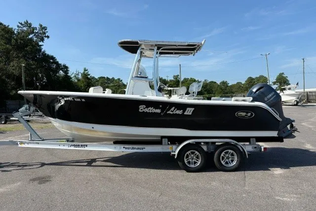 The Image of 2020 Sea Hunt Ultra 225 boat on trailer, black hull, parked outdoors. - 1