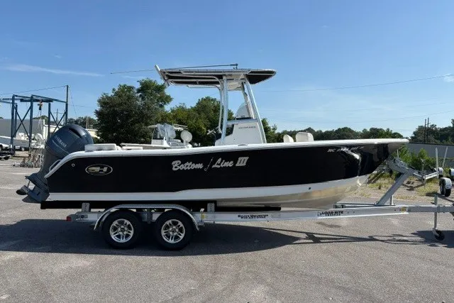 Slide: The Image of 2020 Sea Hunt Ultra 225 boat on trailer, black hull, parked outdoors. - 3