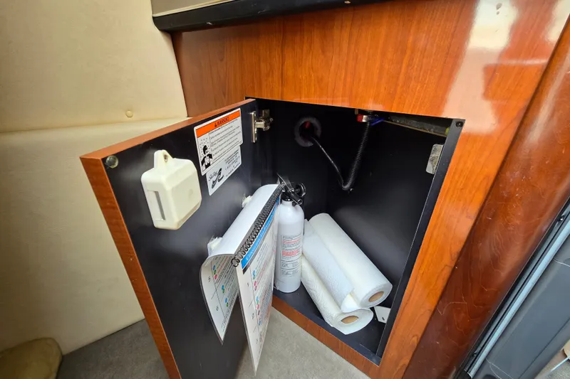 Slide: The Image of Open cabinet on 2006 Sea Ray 240 Sundancer with fire extinguisher and paper towels. - 56