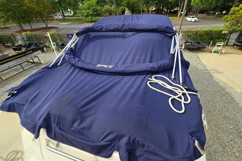 Slide: The Image of 2006 Sea Ray 240 Sundancer boat with blue cover, parked outdoors. - 14