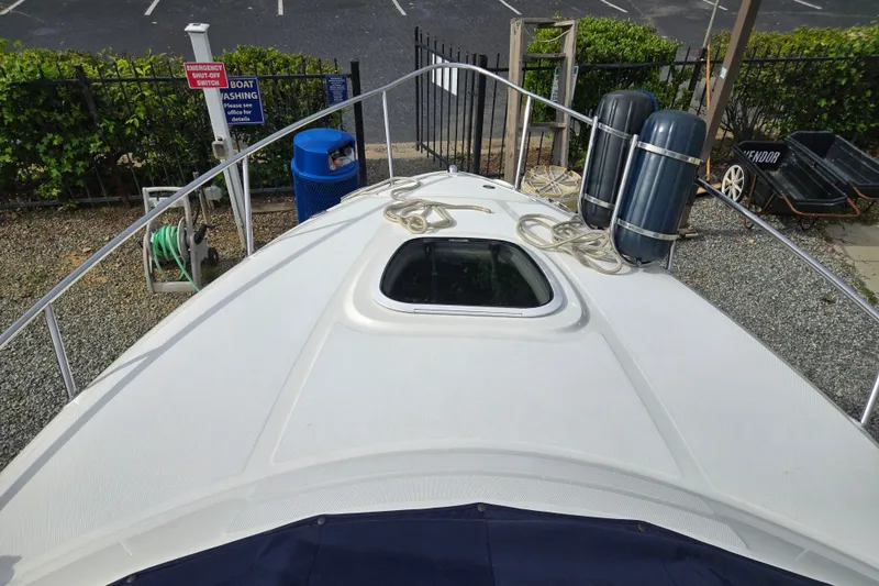 Slide: The Image of 2006 Sea Ray 240 Sundancer boat deck with ropes and hatch, docked near equipment. - 16