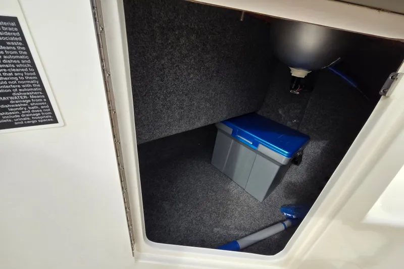 Slide: The Image of Storage compartment in a 2006 Sea Ray 240 Sundancer boat with a blue-lidded container. - 42