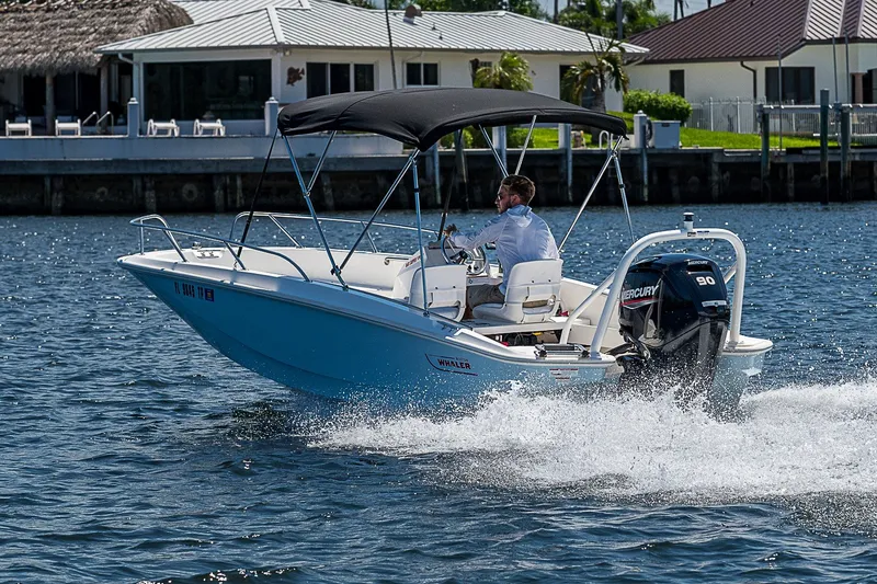 Slide: The Image of 2022 Boston Whaler 160 Super Sport boat cruising on water near waterfront homes. - 36