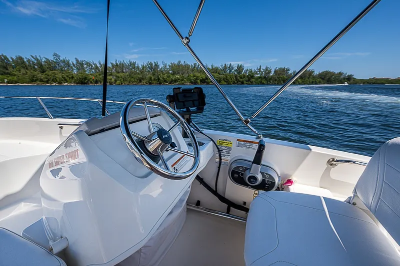 Slide: The Image of 2022 Boston Whaler 160 Super Sport boat interior with steering wheel on a sunny day. - 4