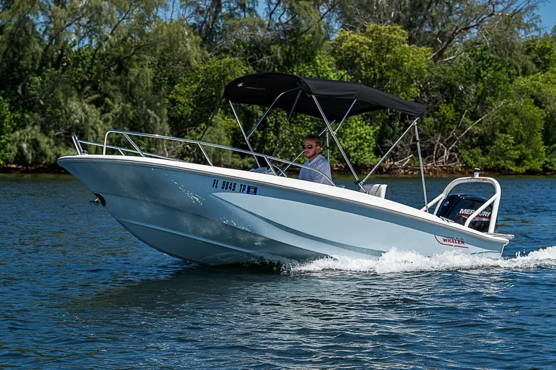Slide: The Image of 2022 Boston Whaler 160 Super Sport boat cruising on a scenic waterway. - 24