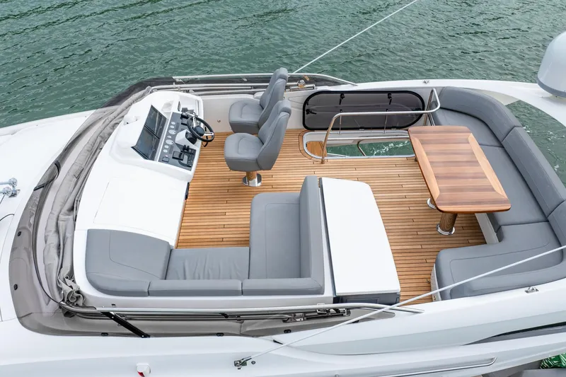 Slide: The Image of 2017 Princess S65 yacht deck with seating, table, and helm, on calm water. - 35