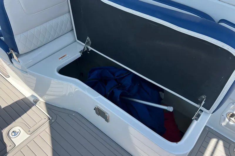 Slide: The Image of Open storage compartment on 2022 Crownline Eclipse E305 XS boat, featuring blue and white seating. - 37