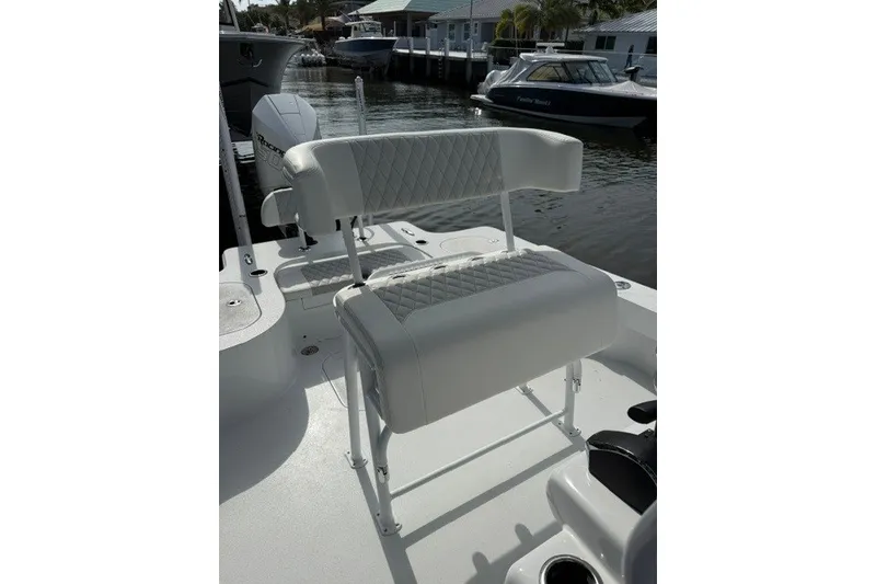 Slide: The Image of 2027 Conch 25 boat with white cushioned seating, docked near waterfront homes. - 5