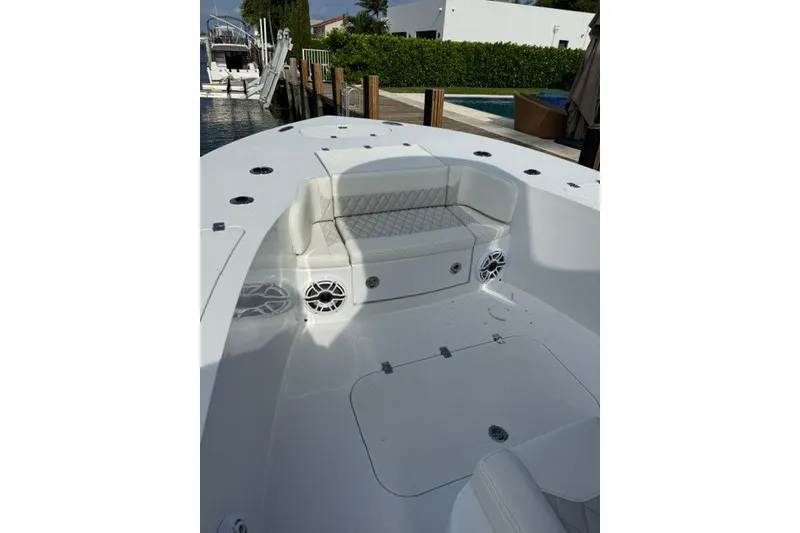 Slide: The Image of 2027 Conch 25 boat interior with cushioned seating and speakers, docked by a waterfront. - 4
