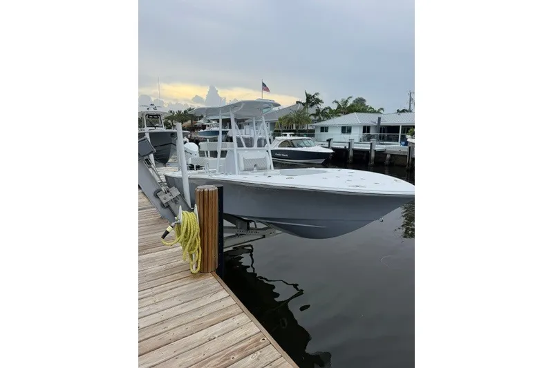 Slide: The Image of 2027 Conch 25 boat docked at marina, calm water, overcast sky. - 2
