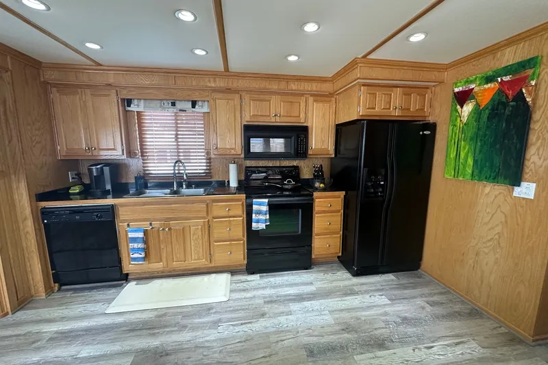 Slide: The Image of Modern kitchen in 2004 Lakeview 16x68 houseboat with wooden cabinets and black appliances. - 4