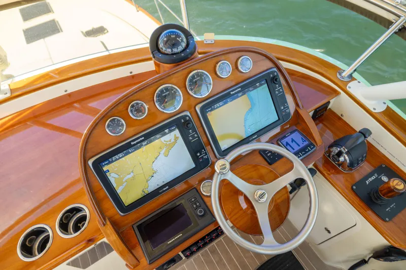 Slide: The Image of Helm of 2014 Hinckley Talaria 48 Flybridge with navigation screens and wooden steering wheel. - 60