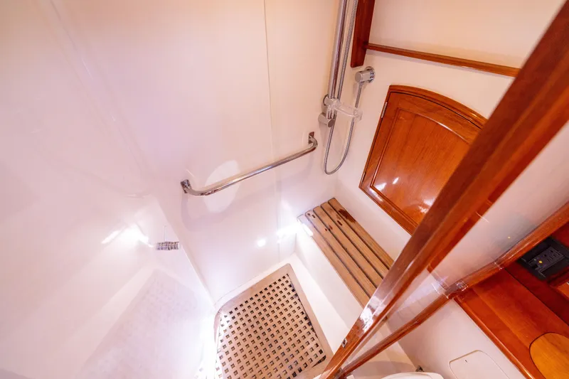 Slide: The Image of 2014 Hinckley Talaria 48 Flybridge shower with wooden bench and chrome fixtures. - 46
