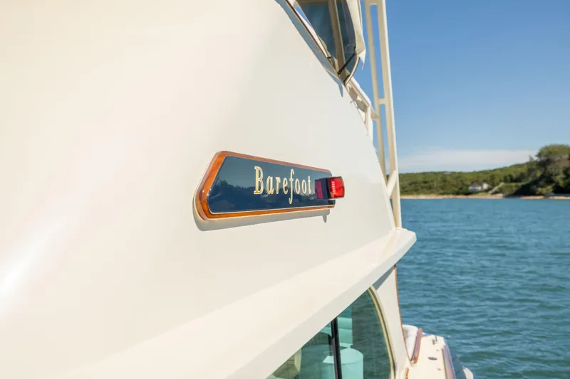 Slide: The Image of 2014 Hinckley Talaria 48 Flybridge yacht on water, featuring "Barefoot" nameplate. - 73
