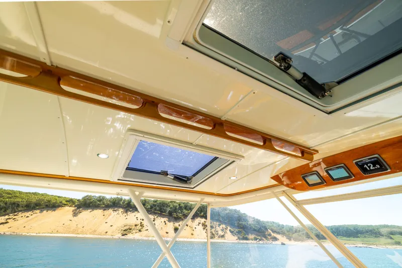 Slide: The Image of 2014 Hinckley Talaria 48 Flybridge interior with skylight, overlooking scenic coastal view. - 63
