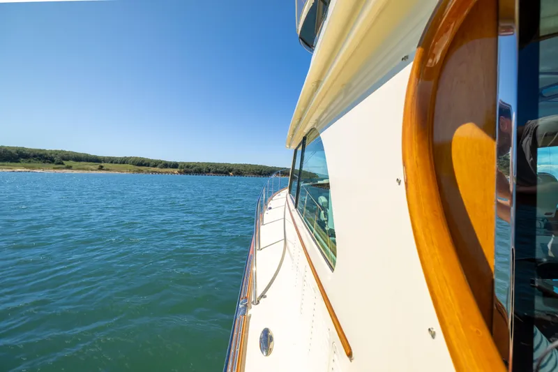 Slide: The Image of 2014 Hinckley Talaria 48 Flybridge cruising on a sunny day, near a scenic shoreline. - 75