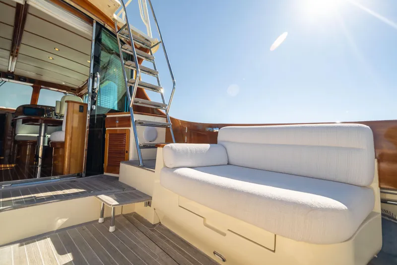 Slide: The Image of 2014 Hinckley Talaria 48 Flybridge yacht with sunlit deck and elegant seating. - 15
