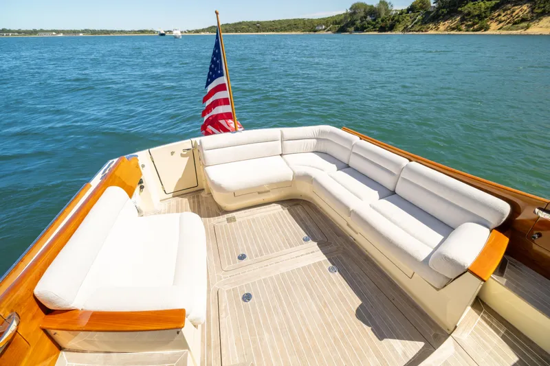 Slide: The Image of Hinckley Talaria 48 Flybridge 2014 yacht deck with seating, American flag, and scenic water view. - 13