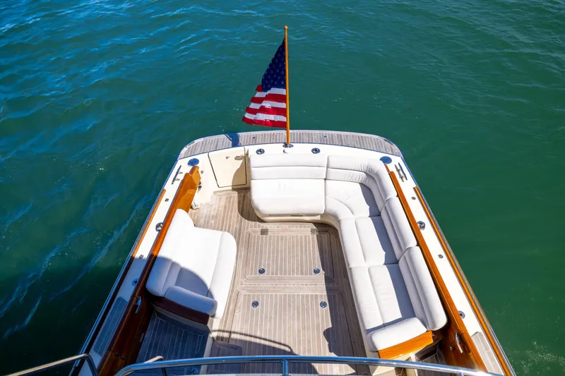 Slide: The Image of Hinckley Talaria 48 Flybridge 2014 yacht with white seating and American flag on deck. - 52