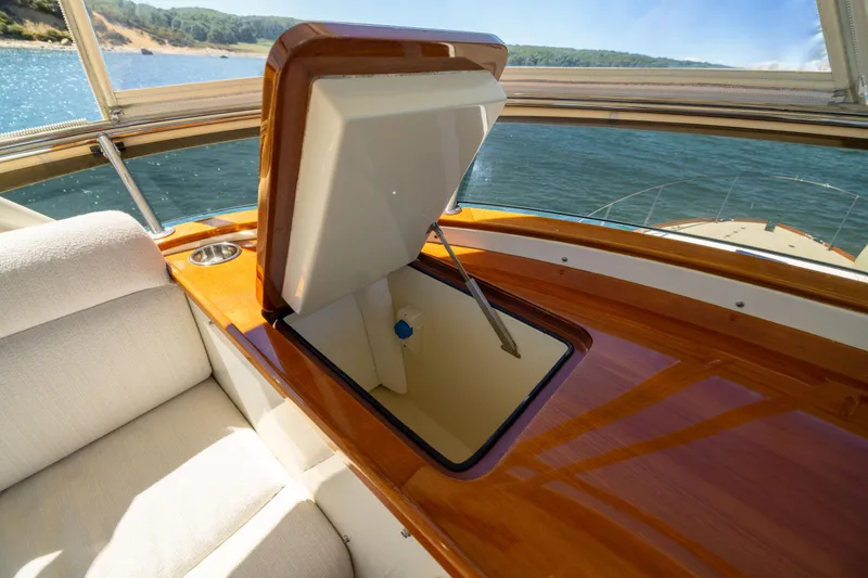 Slide: The Image of Luxurious 2014 Hinckley Talaria 48 Flybridge interior with open storage compartment, overlooking serene waters. - 69