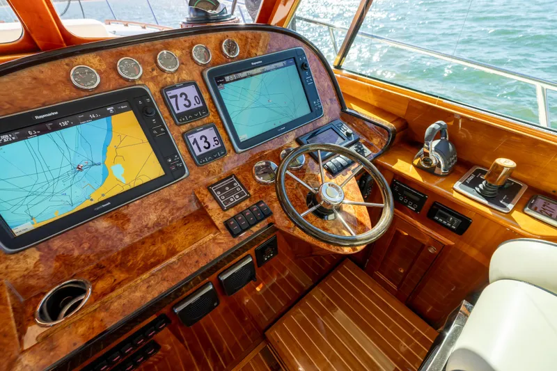 Slide: The Image of Helm of 2014 Hinckley Talaria 48 Flybridge with navigation screens and wooden steering wheel. - 29