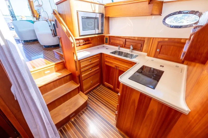 Slide: The Image of Luxurious 2014 Hinckley Talaria 48 Flybridge yacht kitchen with wood cabinetry and modern appliances. - 33