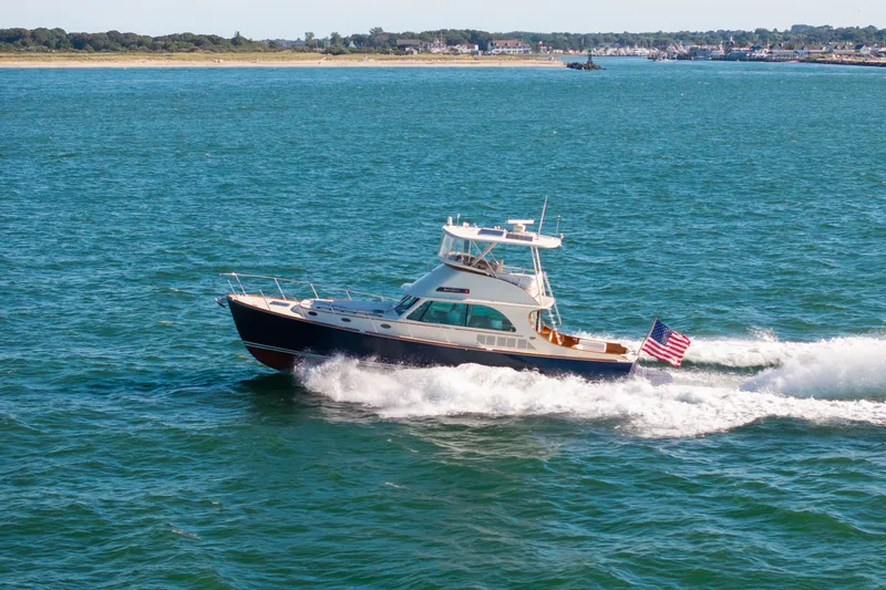 The Image of 2014 Hinckley Talaria 48 Flybridge cruising on open water with American flag. - 0