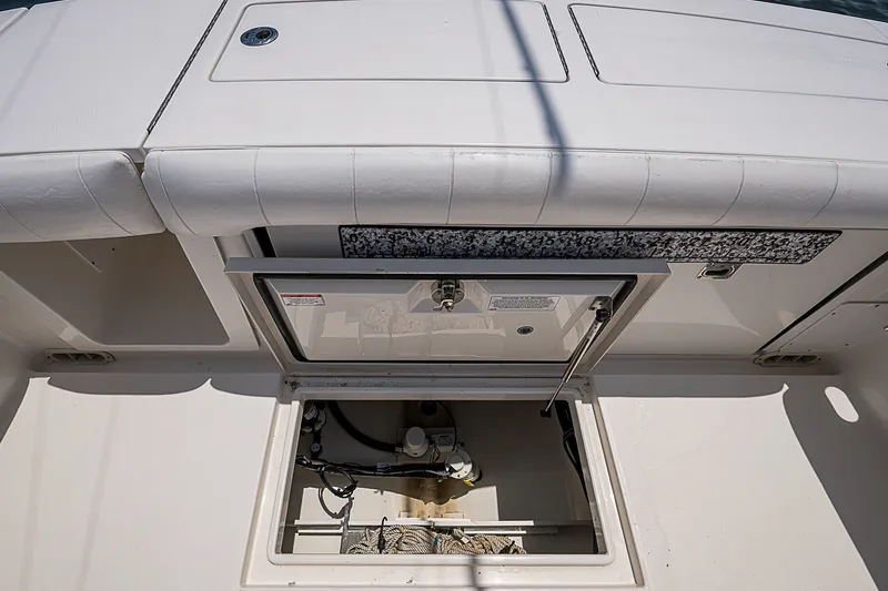 Slide: The Image of 2012 Regulator 28 Forward Seating boat storage compartment open, revealing interior components. - 21