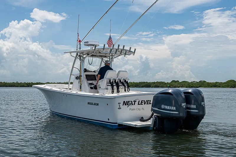 Slide: The Image of 2012 Regulator 28 Forward Seating boat with dual Yamaha engines on calm water. - 13