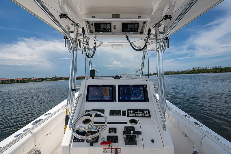 Slide: The Image of 2012 Regulator 28 Forward Seating boat dashboard with navigation screens on a calm waterway. - 26