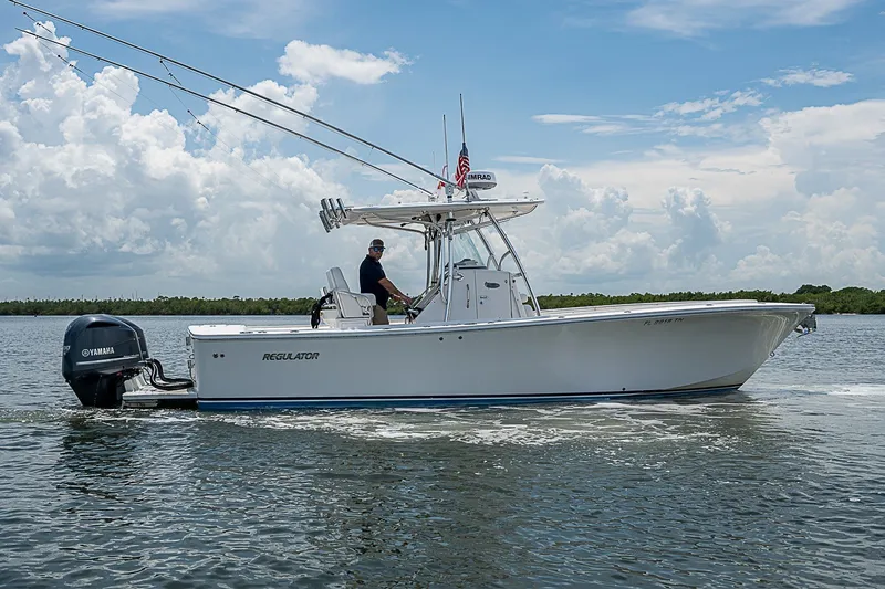 Slide: The Image of 2012 Regulator 28 Forward Seating boat cruising on a calm waterway under a cloudy sky. - 2