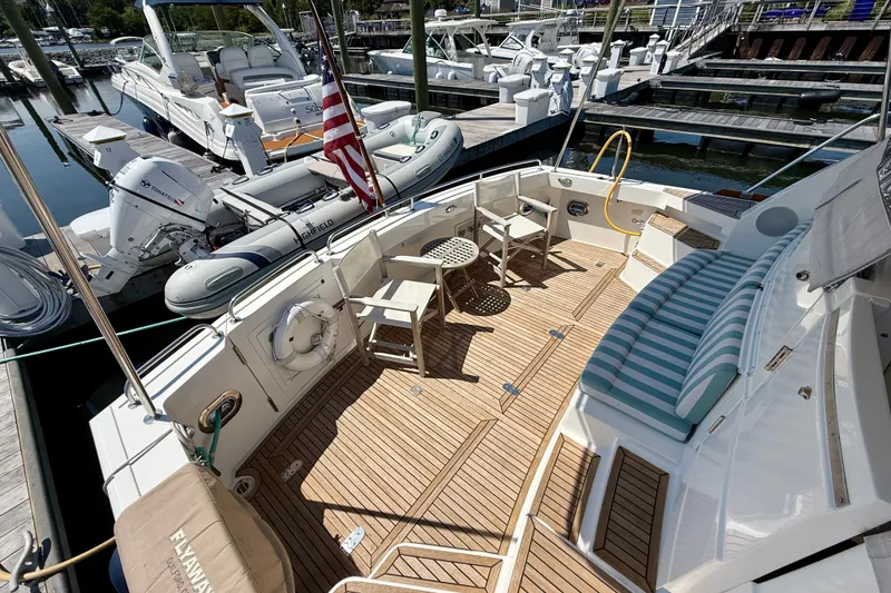 Slide: The Image of 2003 Grand Banks 49 Eastbay HX yacht deck with seating, table, and docked boats. - 34