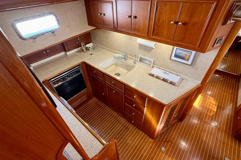Slide: The Image of Luxurious 2003 Grand Banks 49 Eastbay HX yacht kitchen with wood cabinetry and modern appliances. - 50