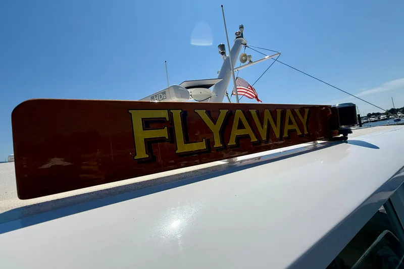 Slide: The Image of 2003 Grand Banks 49 Eastbay HX boat with "FLYAWAY" sign, American flag, clear sky. - 24