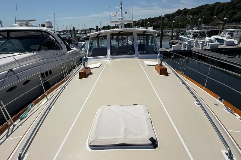 Slide: The Image of 2003 Grand Banks 49 Eastbay HX yacht docked at marina, showcasing spacious deck and sleek design. - 18