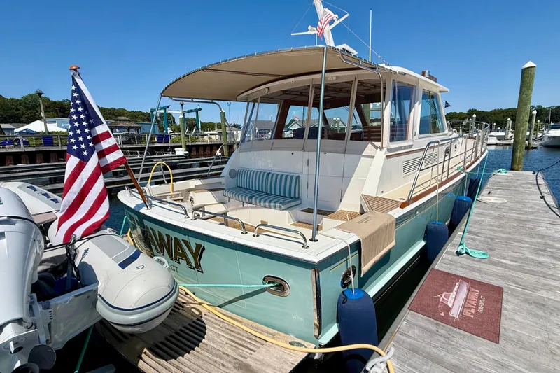 Slide: The Image of 2003 Grand Banks 49 Eastbay HX yacht docked, featuring American flag and tender boat. - 31