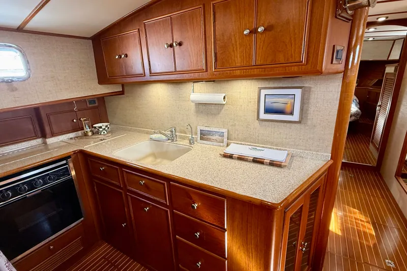 Slide: The Image of Luxurious 2003 Grand Banks 49 Eastbay HX yacht kitchen with wood cabinetry and modern appliances. - 52