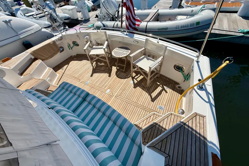Slide: The Image of 2003 Grand Banks 49 Eastbay HX yacht deck with striped seating and wooden chairs. - 35