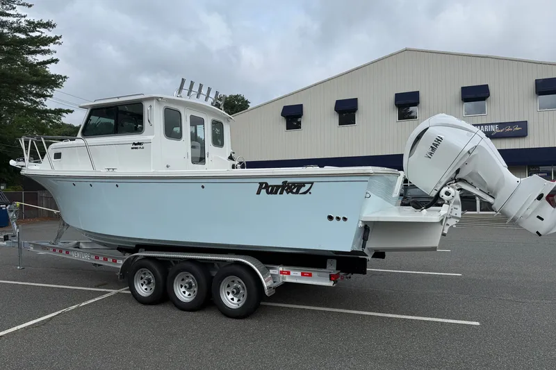 Slide: The Image of 2025 Parker 2520 XLD Sport Cabin boat on trailer, parked outside a building. - 1