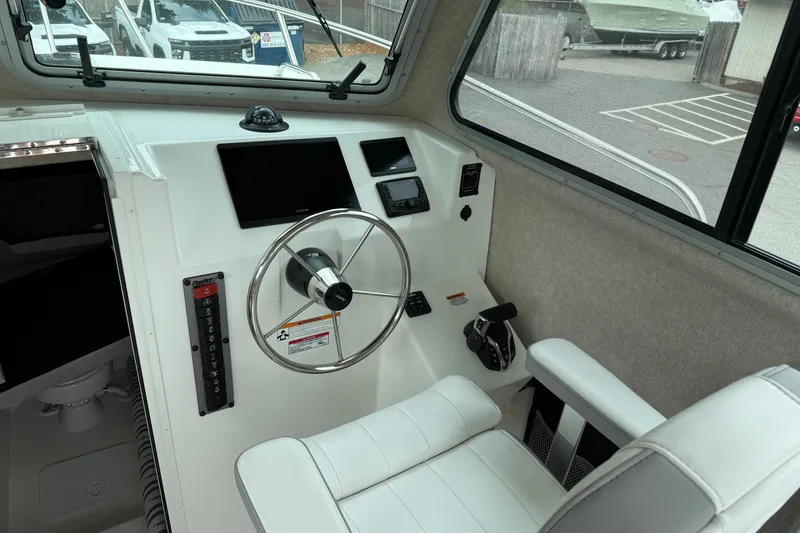 Slide: The Image of 2025 Parker 2520 XLD Sport Cabin helm with steering wheel and navigation controls. - 10