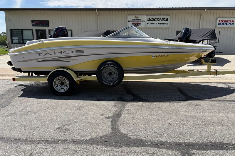The Image of 2004 Tahoe Q4 boat on trailer, yellow and white, parked outside dealership. - 1