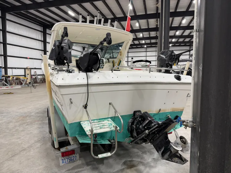 Slide: The Image of A 1999 Sport-Craft Sportsman boat in a warehouse, featuring rod holders and an outboard motor. - 2