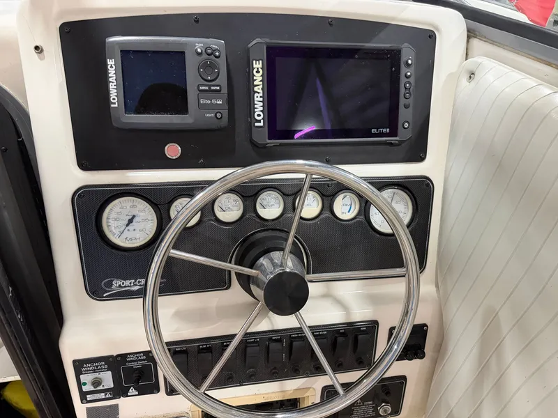 Slide: The Image of The image shows the dashboard of a 1999 Sport-Craft Sportsman with navigation devices and steering wheel. - 12