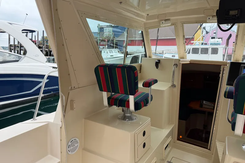 Slide: The Image of Interior of 2006 Albin 28 Gatsby Edition boat with striped seating and docked vessels outside. - 22