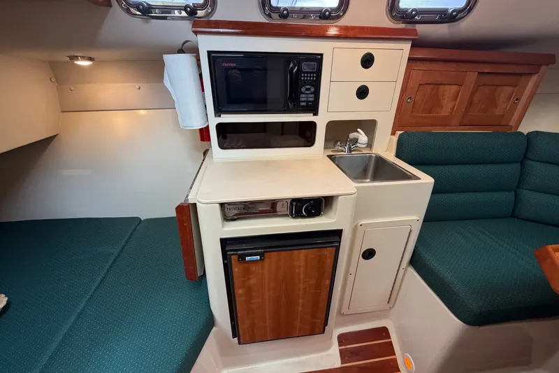 Slide: The Image of Compact galley in 2006 Albin 28 Gatsby Edition boat with microwave, sink, and seating area. - 32