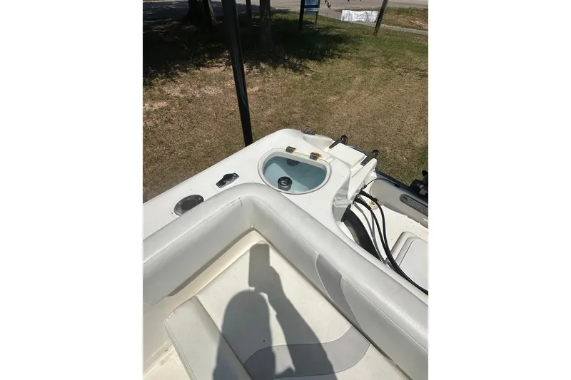 Slide: The Image of 2012 Sundance NX25 boat interior with seating and livewell, parked on grass. - 19