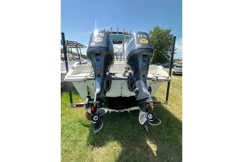 Slide: The Image of 2012 Sundance NX25 boat with dual Yamaha 115 outboard motors, parked on grass. - 15