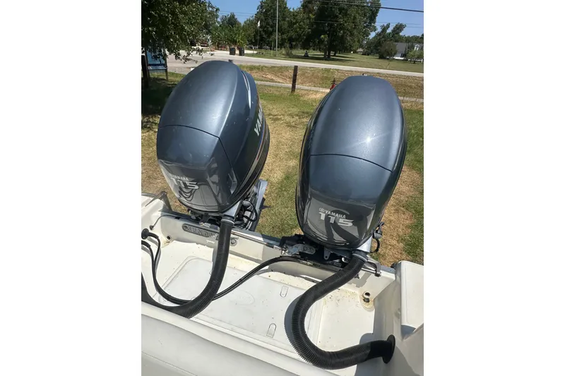 Slide: The Image of Twin Yamaha 115 outboard motors on a 2012 Sundance NX25 boat, parked on grass. - 39