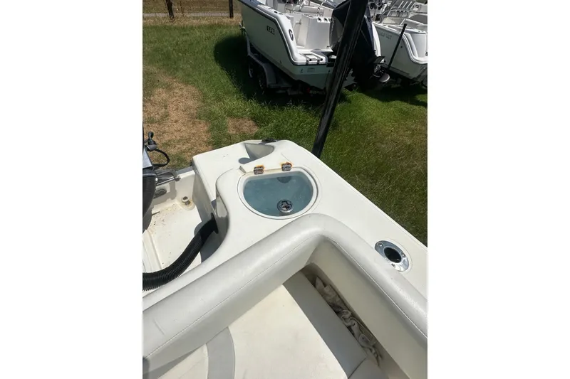 Slide: The Image of 2012 Sundance NX25 boat interior with livewell and seating, parked on grass. - 18