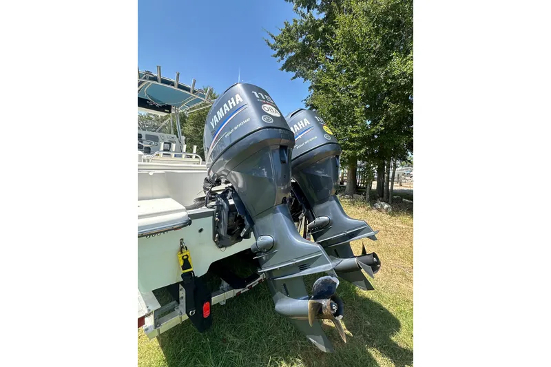 Slide: The Image of Twin Yamaha outboard motors on a 2012 Sundance NX25 boat, parked on grass. - 16